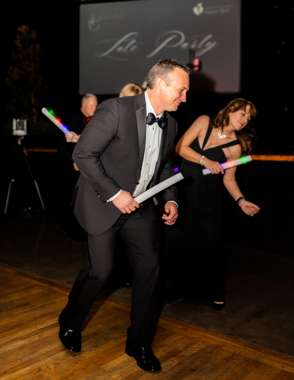 People holding glow sticks dancing at the Late Party.